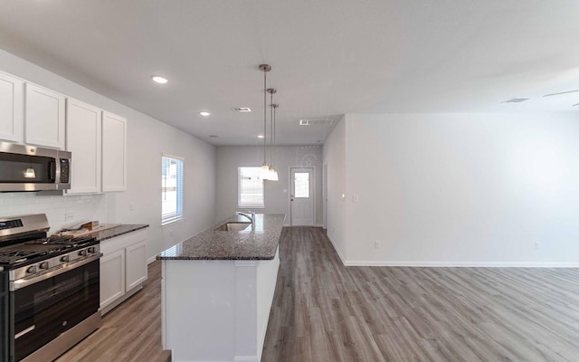 kitchen with tasteful backsplash, visible vents, light wood-style flooring, appliances with stainless steel finishes, and a sink