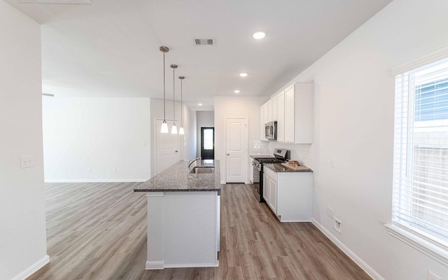 kitchen with visible vents, white cabinets, decorative backsplash, dark stone countertops, and stainless steel appliances