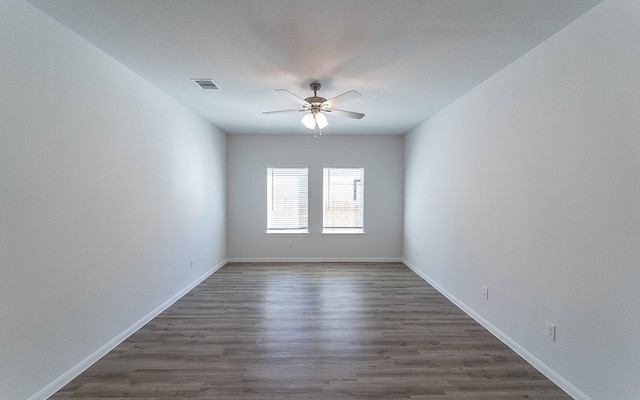 unfurnished room featuring ceiling fan, visible vents, baseboards, and dark wood finished floors