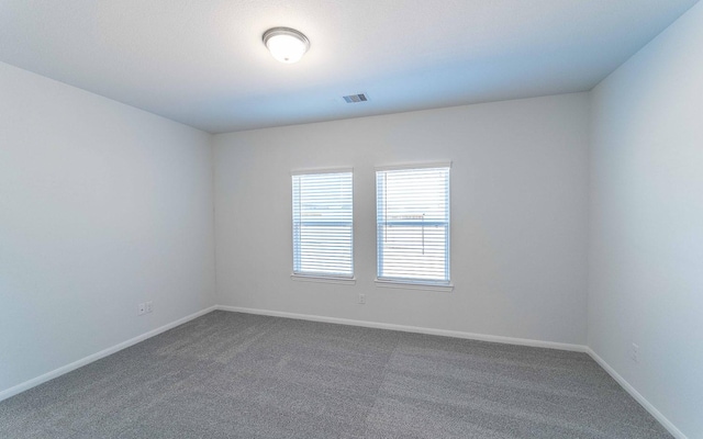 unfurnished room featuring dark carpet, visible vents, and baseboards