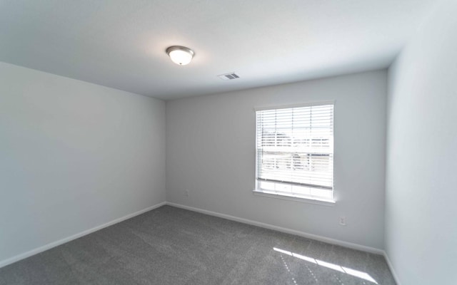 unfurnished room with carpet flooring, visible vents, and baseboards