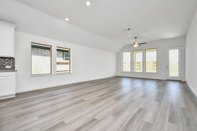 unfurnished living room featuring ceiling fan, a healthy amount of sunlight, lofted ceiling, and light hardwood / wood-style flooring