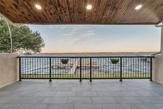 balcony at dusk featuring a water view