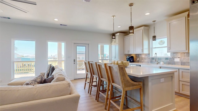 kitchen featuring pendant lighting, light wood-type flooring, white cabinetry, and sink