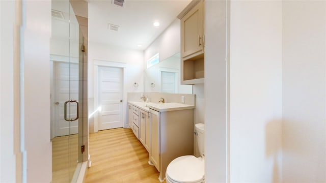 bathroom featuring vanity, hardwood / wood-style flooring, toilet, and a shower with shower door