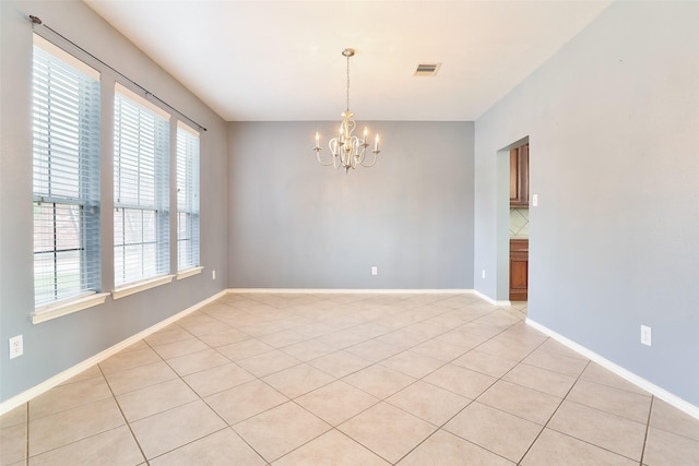 empty room with light tile patterned flooring and an inviting chandelier