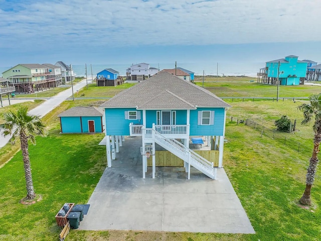 coastal inspired home with a carport, a porch, and a front lawn