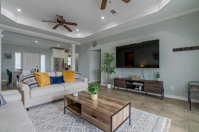 living room featuring decorative columns, a raised ceiling, ceiling fan, and ornamental molding