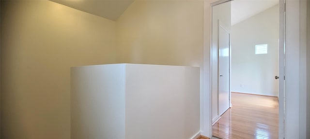 corridor featuring light hardwood / wood-style flooring and lofted ceiling