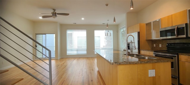 kitchen featuring light wood-type flooring, tasteful backsplash, stainless steel appliances, ceiling fan, and sink