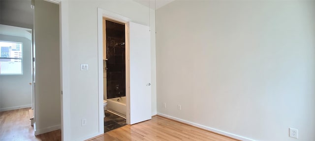 unfurnished bedroom with ensuite bath and light hardwood / wood-style floors