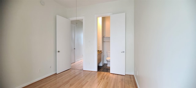 unfurnished bedroom with connected bathroom, a closet, and light wood-type flooring