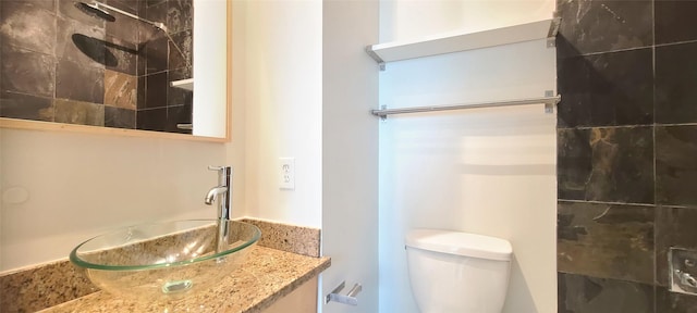 bathroom with a tile shower, toilet, and sink