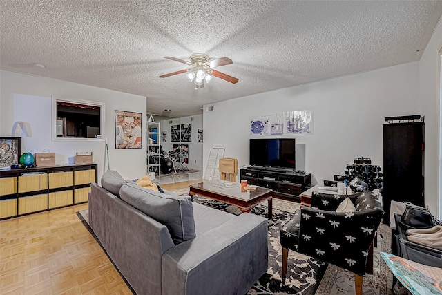 living room featuring ceiling fan, light parquet floors, and a textured ceiling