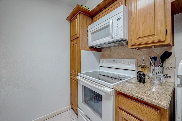 kitchen with backsplash, light stone countertops, light tile patterned flooring, and white appliances