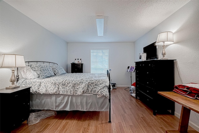 bedroom featuring a textured ceiling and light hardwood / wood-style flooring