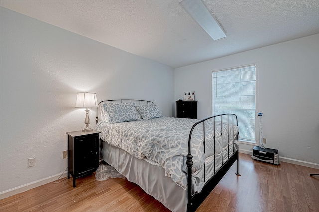 bedroom with hardwood / wood-style floors and a textured ceiling