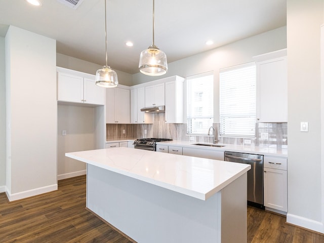 kitchen featuring tasteful backsplash, a kitchen island, sink, white cabinetry, and stainless steel appliances