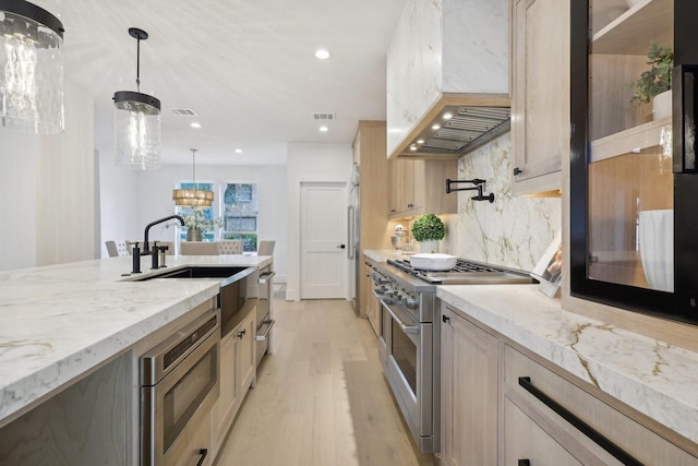 kitchen with hanging light fixtures, light wood-type flooring, light brown cabinetry, custom range hood, and stainless steel appliances