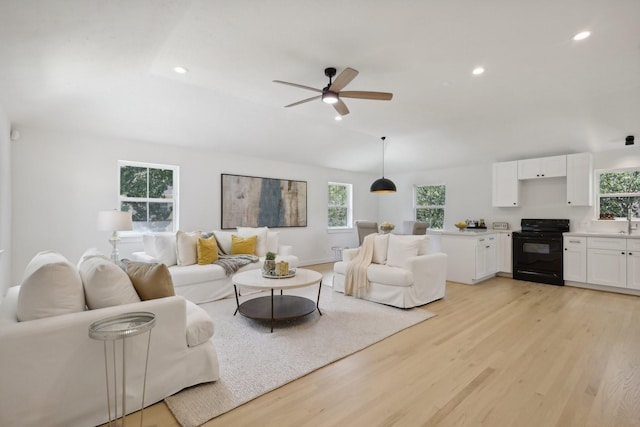 living room with ceiling fan, sink, and light wood-type flooring