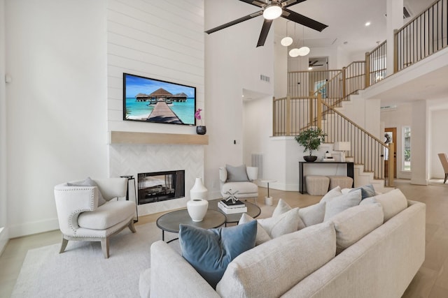 living room featuring ceiling fan, a towering ceiling, and a fireplace