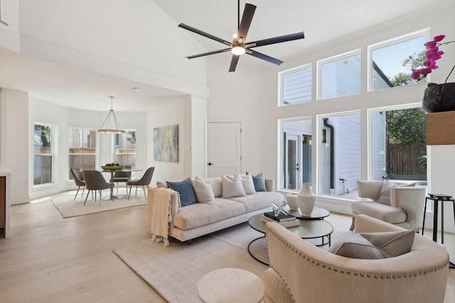 living room featuring ceiling fan, a towering ceiling, and light hardwood / wood-style floors