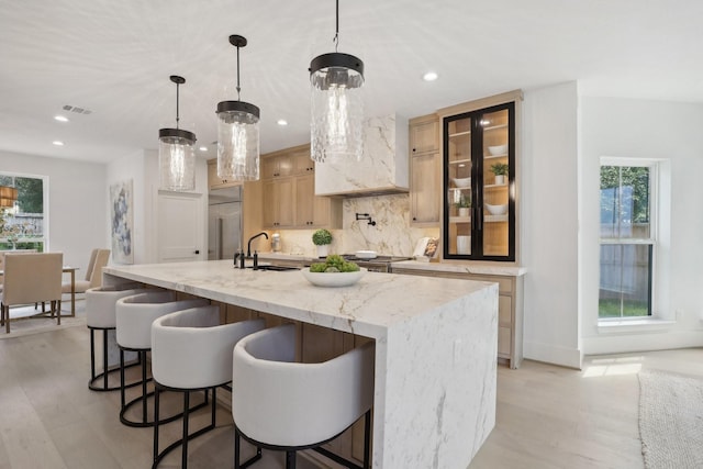 kitchen with a large island, decorative light fixtures, a healthy amount of sunlight, and light brown cabinetry