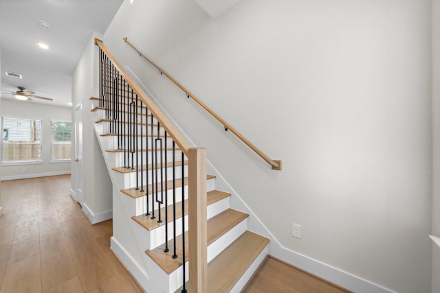 staircase featuring wood-type flooring and ceiling fan