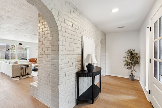 hall featuring light hardwood / wood-style floors and brick wall