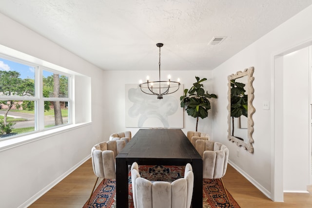 dining area featuring hardwood / wood-style floors, a textured ceiling, and an inviting chandelier