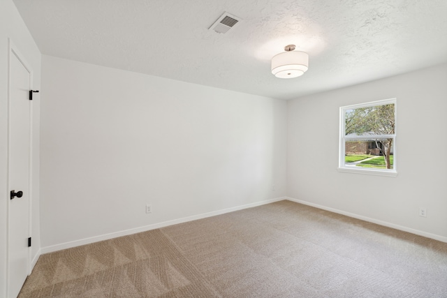 empty room with light colored carpet and a textured ceiling