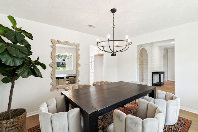 dining space with light hardwood / wood-style flooring and a chandelier