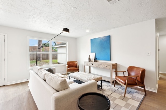 living room featuring light wood-type flooring and a textured ceiling