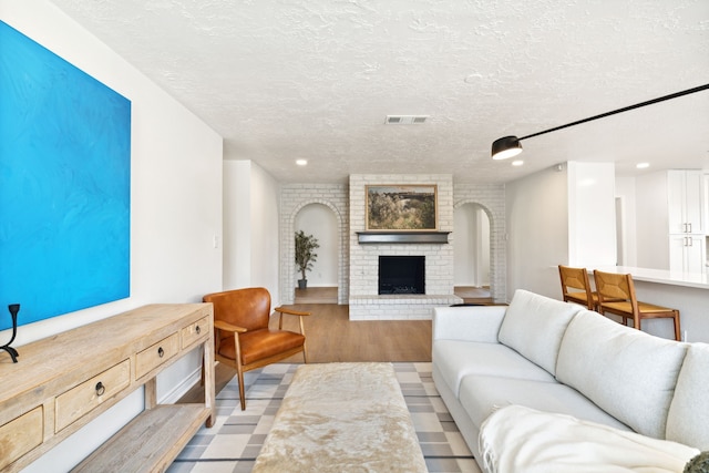 living room featuring a fireplace, a textured ceiling, and light wood-type flooring