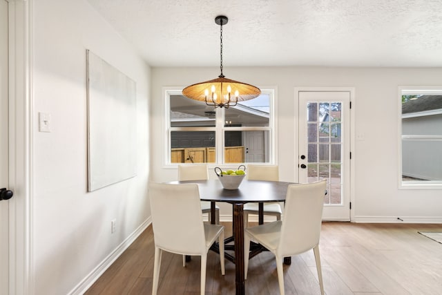 dining area featuring hardwood / wood-style floors, a textured ceiling, and a notable chandelier