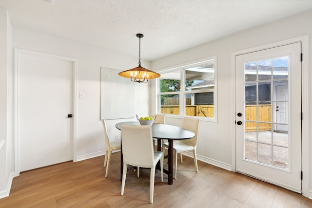 dining room featuring a textured ceiling, light wood-type flooring, and a wealth of natural light