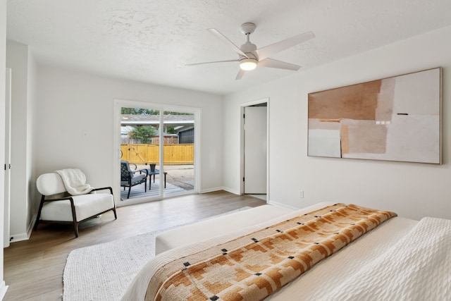 bedroom with ceiling fan, light hardwood / wood-style floors, access to exterior, and a textured ceiling