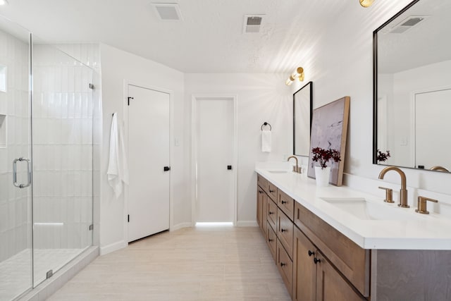 bathroom with vanity, an enclosed shower, and a textured ceiling