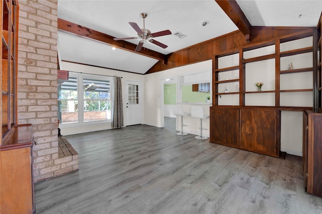 unfurnished living room with ceiling fan, lofted ceiling with beams, and light wood-type flooring