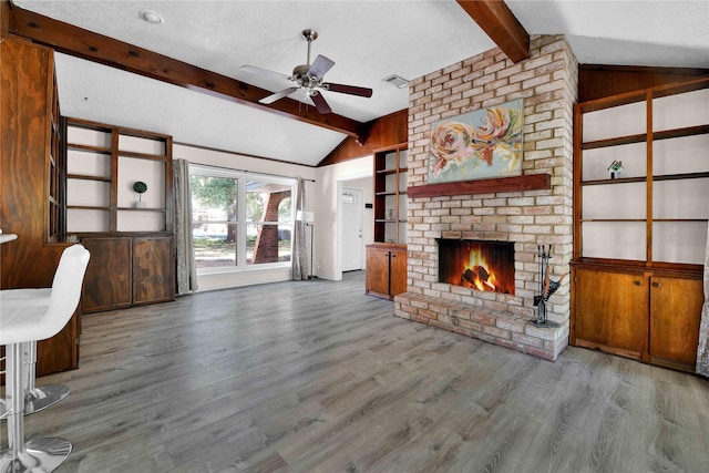 unfurnished living room featuring vaulted ceiling with beams, a fireplace, a textured ceiling, and hardwood / wood-style flooring