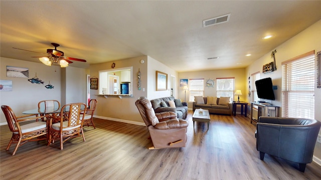 living room with light wood-type flooring, a wealth of natural light, and ceiling fan