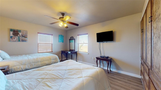 bedroom with hardwood / wood-style flooring, ceiling fan, and multiple windows