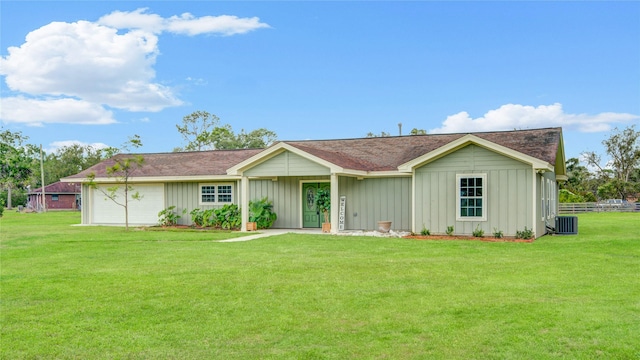 ranch-style home with a garage, a front lawn, and central air condition unit