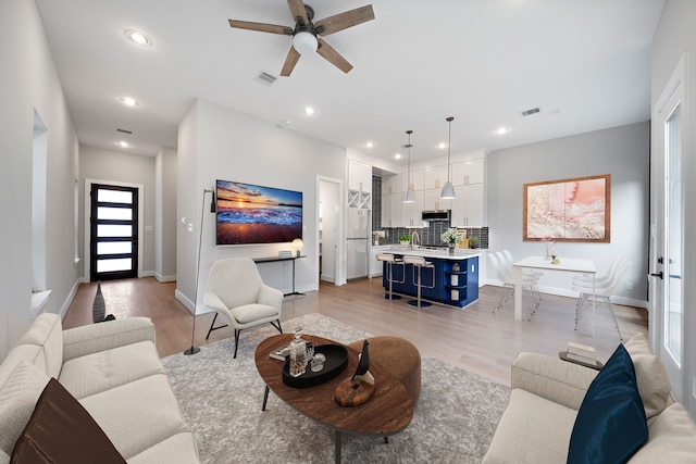 living room featuring sink, ceiling fan, and light hardwood / wood-style flooring