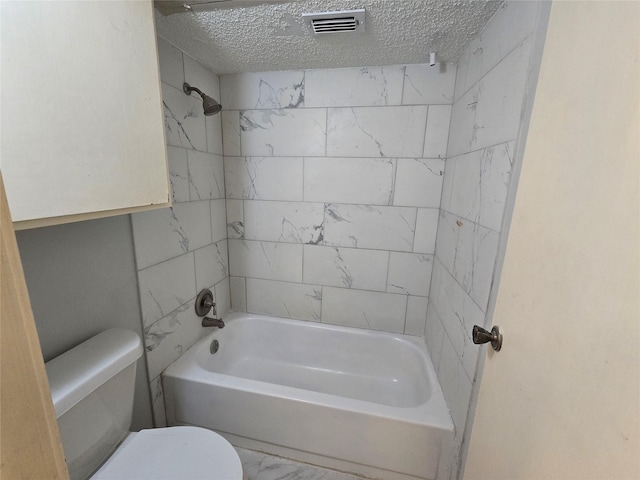 bathroom featuring toilet, a textured ceiling, and tiled shower / bath