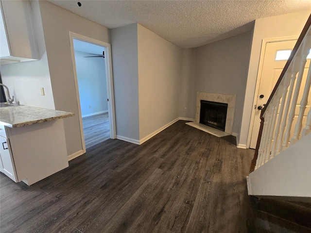 living room featuring a textured ceiling, dark hardwood / wood-style flooring, and a premium fireplace