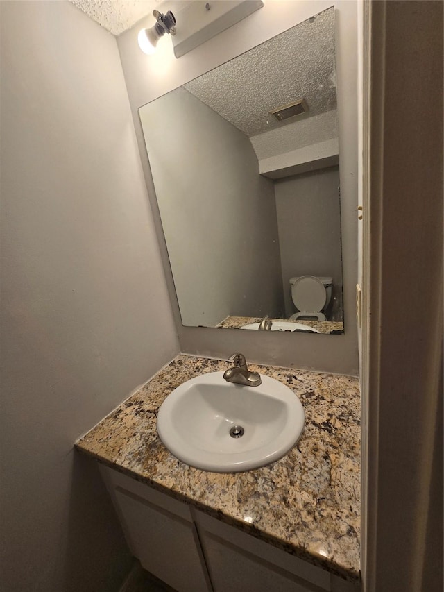 bathroom with vanity, a textured ceiling, and toilet