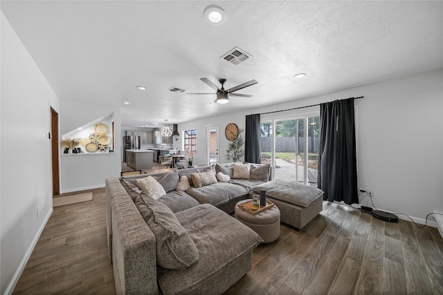 living room featuring ceiling fan, dark wood-type flooring, and a textured ceiling