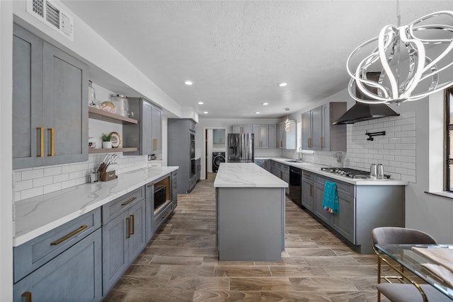 kitchen featuring sink, stainless steel appliances, gray cabinets, a kitchen island, and hardwood / wood-style flooring