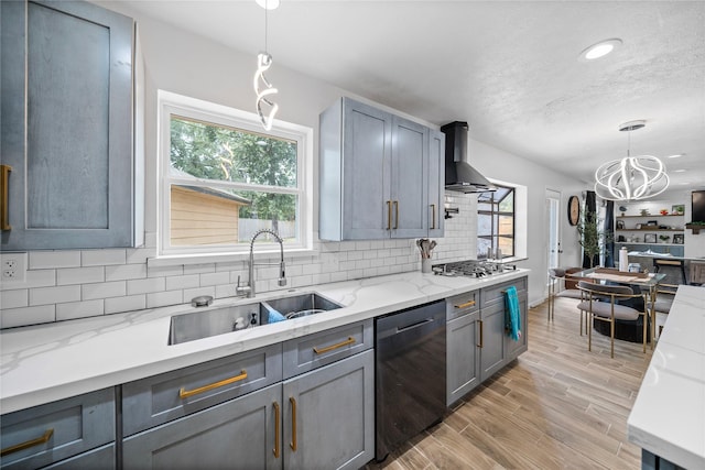 kitchen featuring wall chimney exhaust hood, sink, decorative light fixtures, dishwasher, and gray cabinets